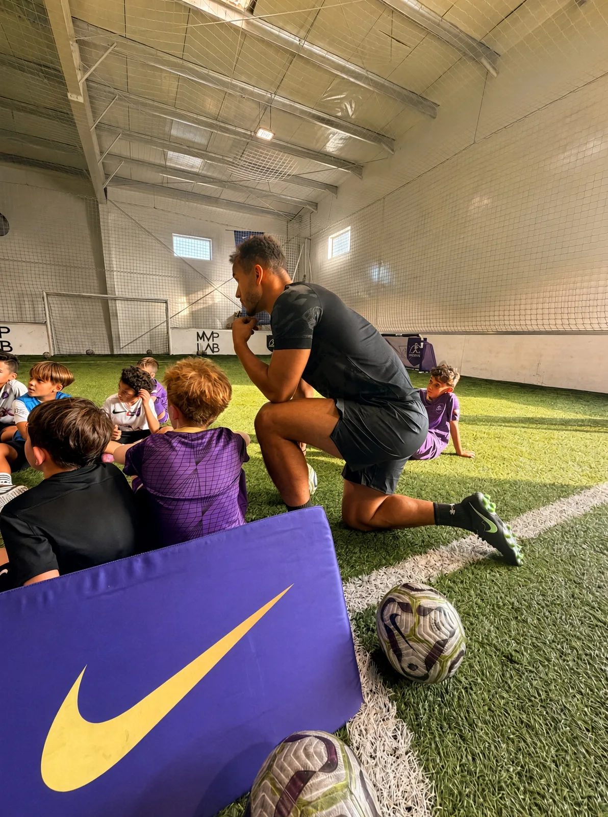 Coach Jerome kneeling with a group of young players indoors